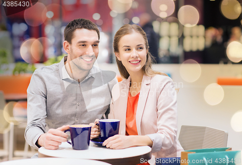 Image of happy couple with shopping bags drinking coffee