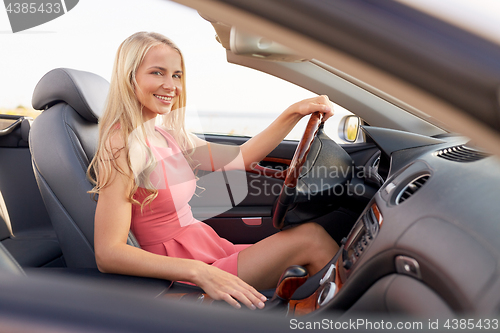 Image of happy young woman in convertible car