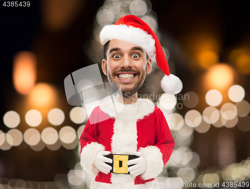 Image of man in santa claus costume over christmas lights