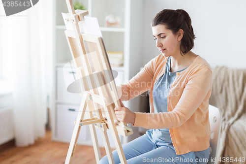Image of artist with easel drawing picture at art studio
