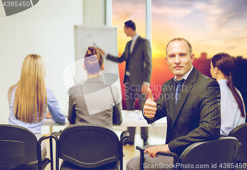 Image of businessman with team showing thumbs up at office