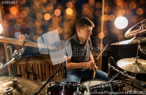 Image of musician playing drum kit at concert over lights