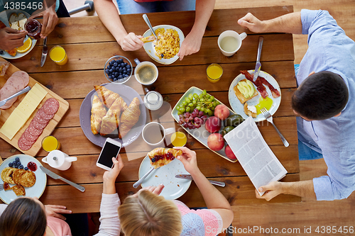 Image of people with smartphones eating food at table