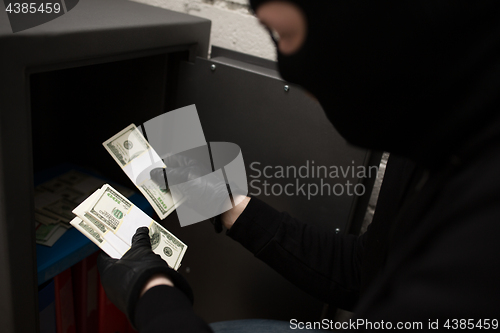 Image of thief stealing money from safe at crime scene