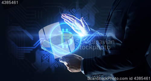 Image of businessman with tablet pc and bitcoin hologram