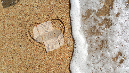 Image of Heart drawing in the sand and sea foam