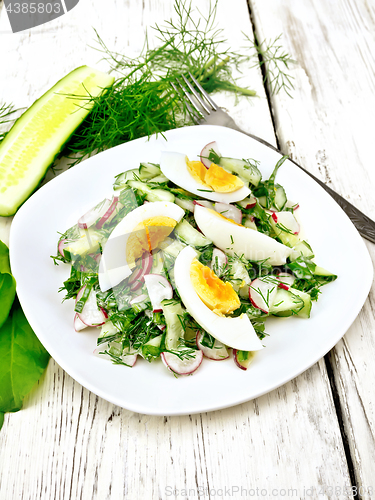 Image of Salad with radish and egg in plate on wooden table