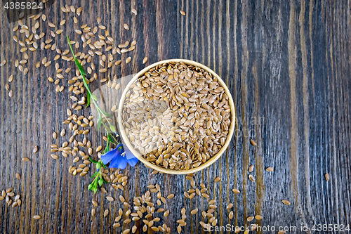 Image of Flaxen brown seed in bowl with flower on board top