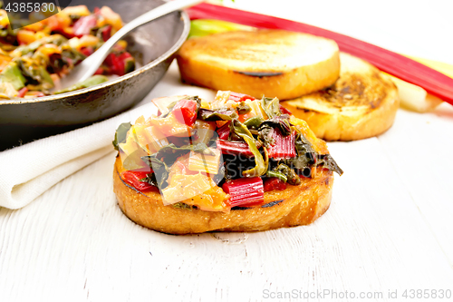 Image of Bruschetta with stewed chard and orange on board