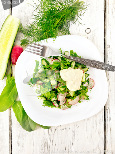 Image of Salad with radishes and sorrel in plate on board top