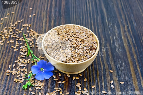 Image of Flaxen brown seed in bowl with flower on dark board