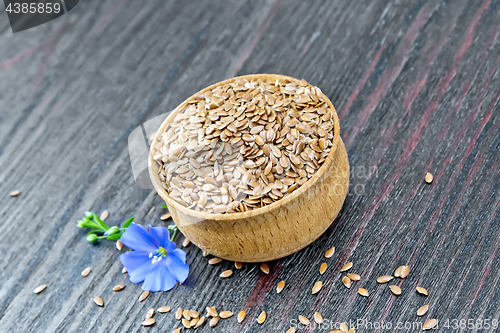 Image of Flaxen brown seed in bowl with flower on board
