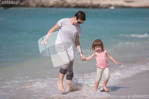 Image of mother and daughter running on the beach
