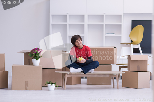 Image of boy sitting on the table with cardboard boxes around him