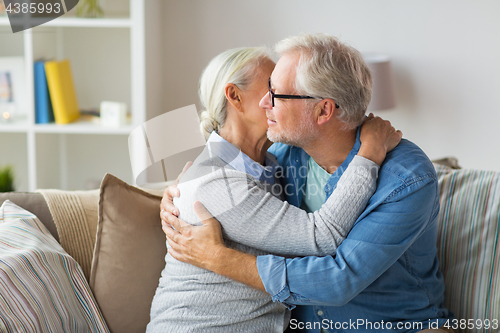 Image of happy senior couple hugging at home