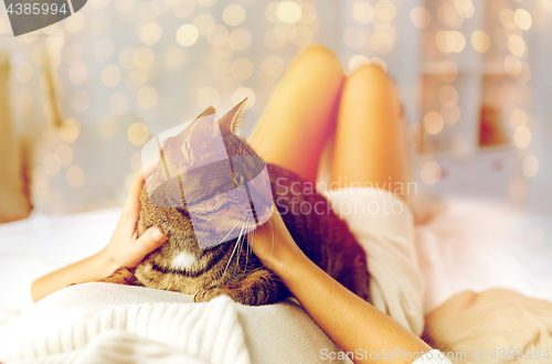 Image of young woman with cat lying in bed at home