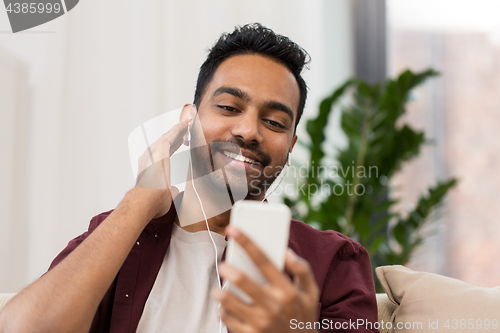 Image of man in earphones listening to music on smartphone