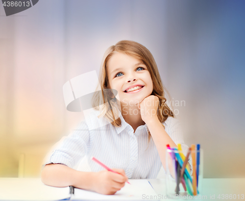 Image of smiling little student girl drawing at school