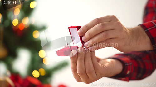 Image of close up of hands with ring in christmas gift box