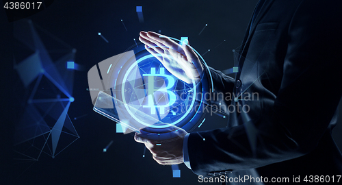 Image of businessman with tablet pc and bitcoin hologram