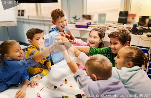 Image of happy children making high five at robotics school