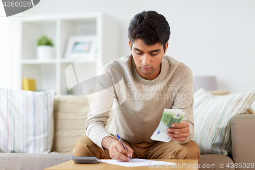 Image of man with money and calculator filling papers