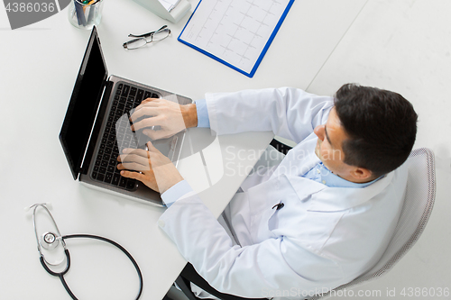 Image of doctor with cardiogram and laptop at clinic