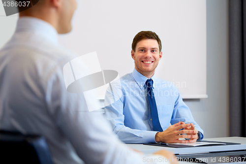 Image of happy coworkers meeting and talking at office