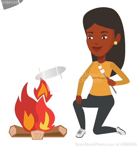 Image of Woman roasting marshmallow over campfire.