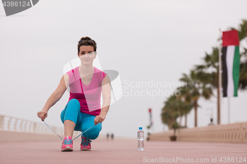 Image of Young woman tying shoelaces on sneakers