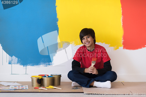 Image of young boy painter resting after painting the wall