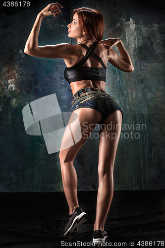 Image of Muscular young woman athlete on black