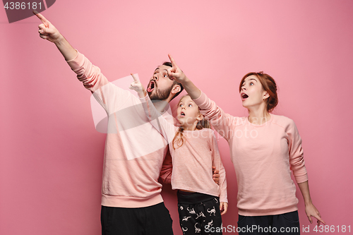 Image of Surprised young family on pink