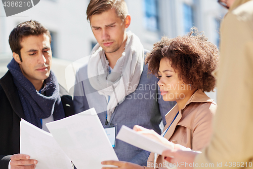 Image of international business team with papers outdoors