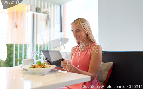 Image of happy young woman with tablet pc at restaurant