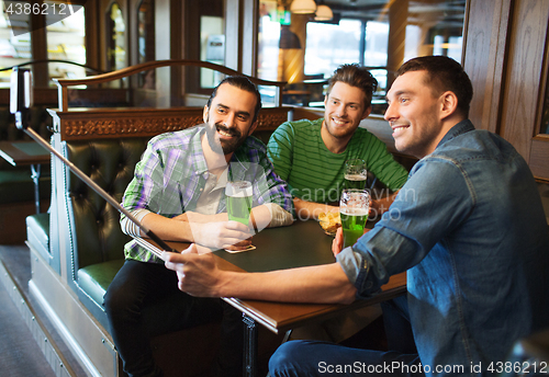 Image of friends taking selfie with green beer at pub