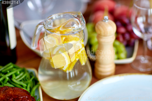 Image of glass jug of lemon water and food on table