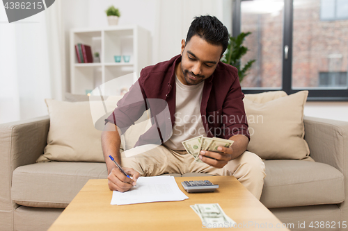 Image of man with money and calculator filling papers