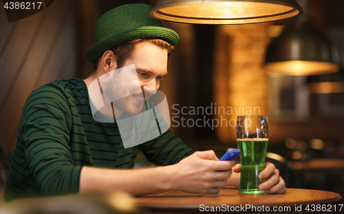 Image of man with smartphone and green beer at bar or pub