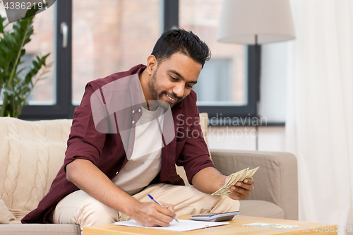 Image of man with money and calculator filling papers