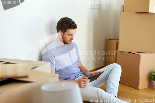 Image of man with tablet pc and boxes moving to new home