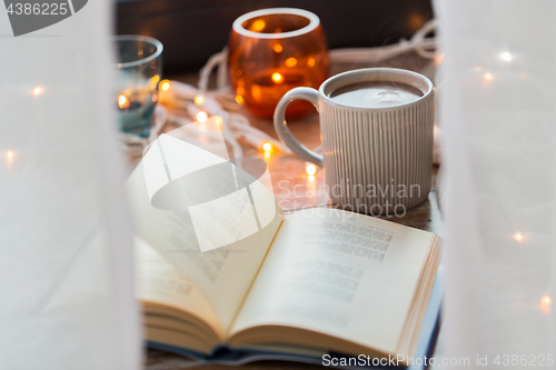 Image of book and cup of coffee or hot chocolate on table