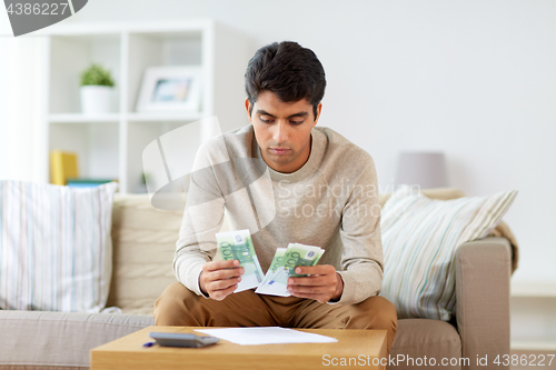 Image of man counting money at home