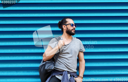 Image of man in sunglasses with bag standing at street wall