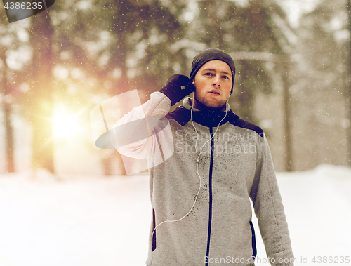 Image of sports man with earphones in winter forest