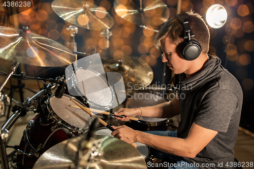 Image of musician playing drum kit at concert over lights