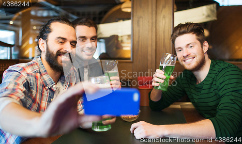 Image of friends taking selfie with green beer at pub