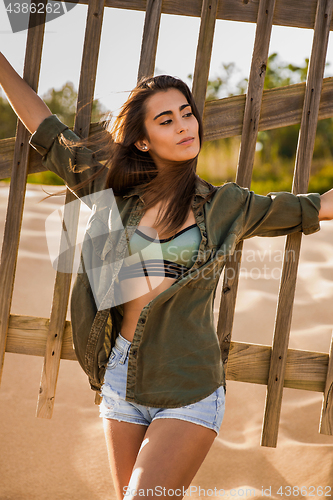 Image of Beautiful young woman posing near a wood fence