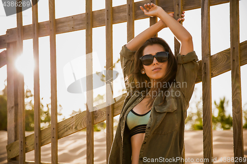 Image of Beautiful young woman posing near a wood fence