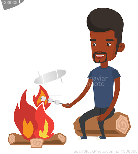 Image of Man roasting marshmallow over campfire.